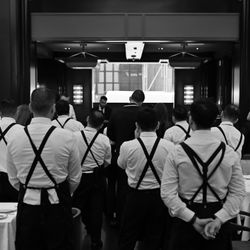 Staff at a steak house restaurant wearing white shirts and black suspenders standing in a formal dining area.