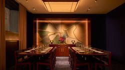 Elegant private dining room with two long tables, modern chairs, and decorative floral art in a French restaurant.