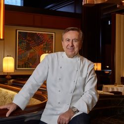 Daniel Boulud in chef coat inside an elegant steakhouse, highlighting the celebrity chef steakhouse ambiance in NYC.