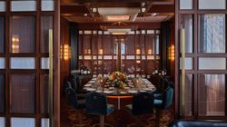 Private dining room in French steakhouse featuring a round table, elegant table settings, and dark wood paneling.