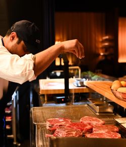 Chef seasoning raw steaks in a kitchen at La Tête d'Or by Daniel steakhouse in NYC.