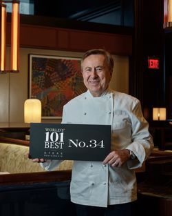 Chef in a white jacket holding a sign ranking the steakhouse as No. 34 in the world's 101 best steak restaurants.