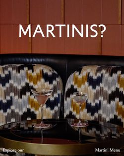 Two martini glasses on a round table with patterned chairs and a wooden panel backdrop at La Tête d'Or by Daniel.