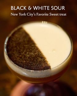 Close-up of a Black & White Sour cocktail with a distinct half-black, half-white foam top, served at La Tête d'Or by Daniel.