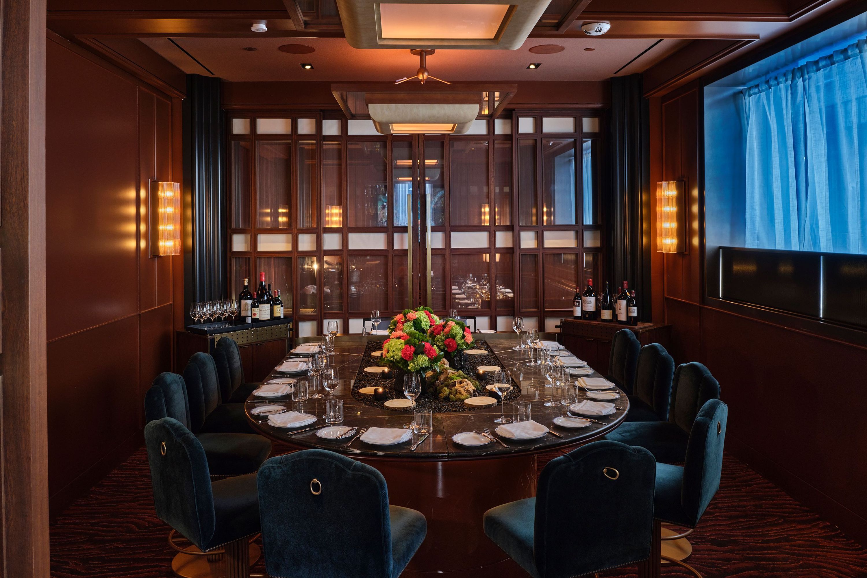 Elegant private dining room at La Tête d'Or by Daniel, featuring a round table, plush chairs, and floral centerpiece.