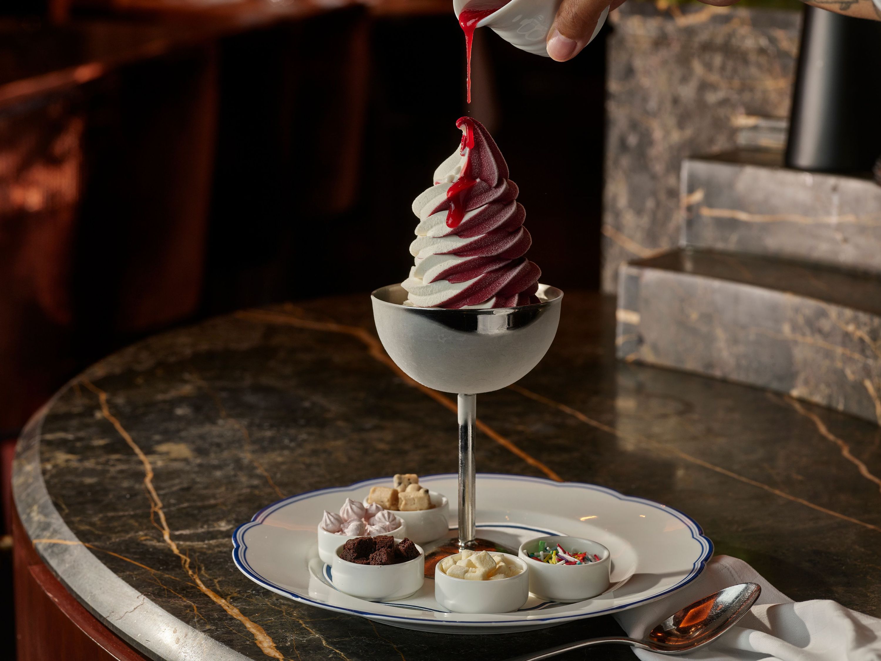 A delicious dessert featuring soft serve ice cream topped with a fruit sauce, served with assorted toppings.