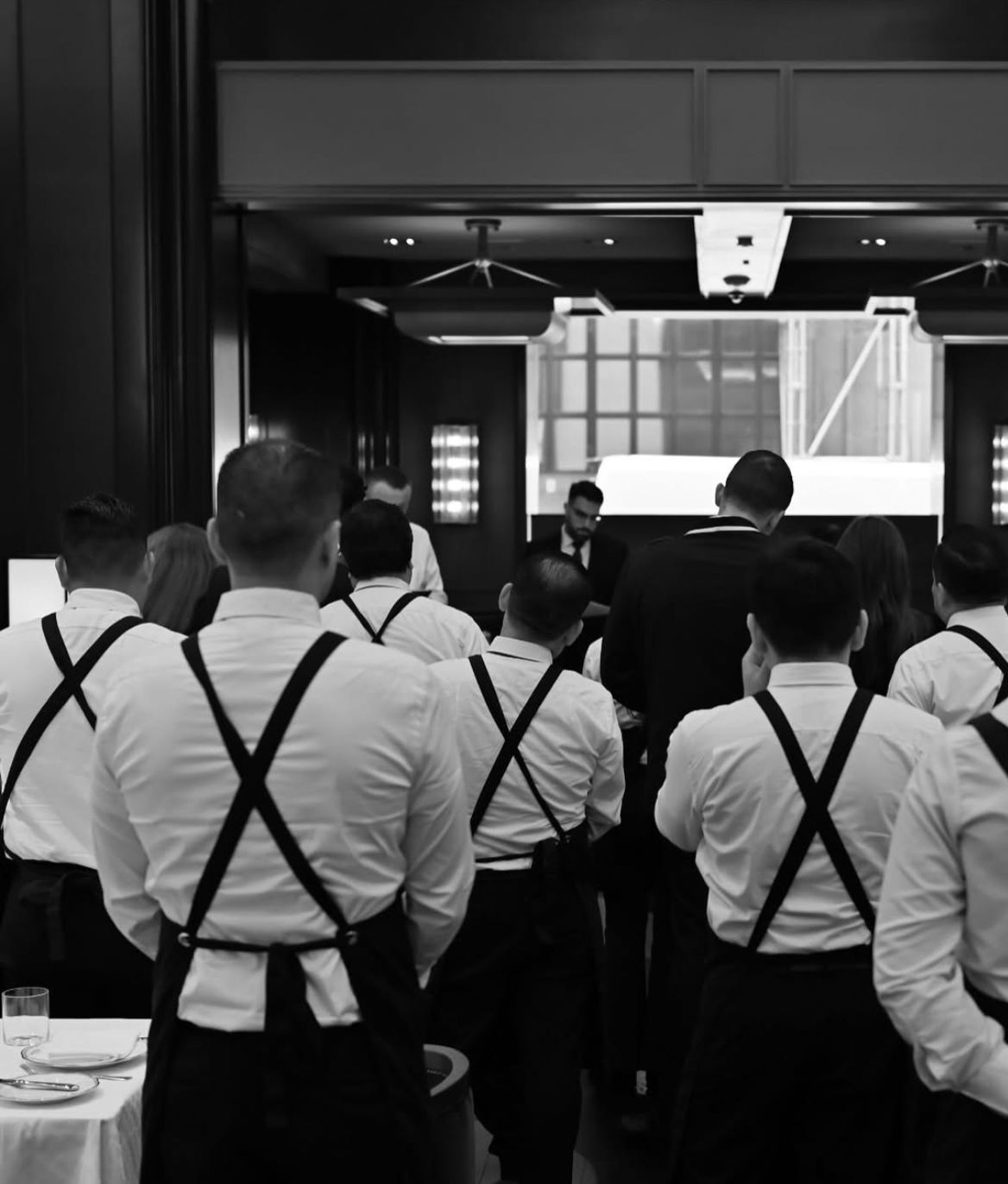 A formal dining scene at La Tête d'Or, featuring waitstaff in white shirts and black suspenders, ready to serve.